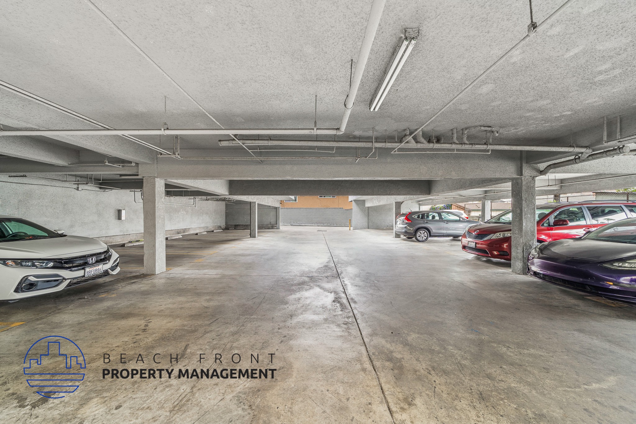 A parking garage with a white car on the left and a red car on the right.